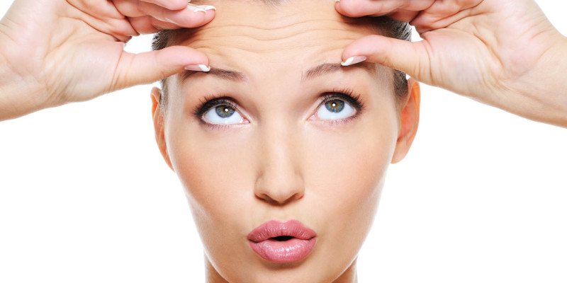 Woman examines her wrinkly forehead before treatment at Elan Medical Skin Clinic, Essex and London